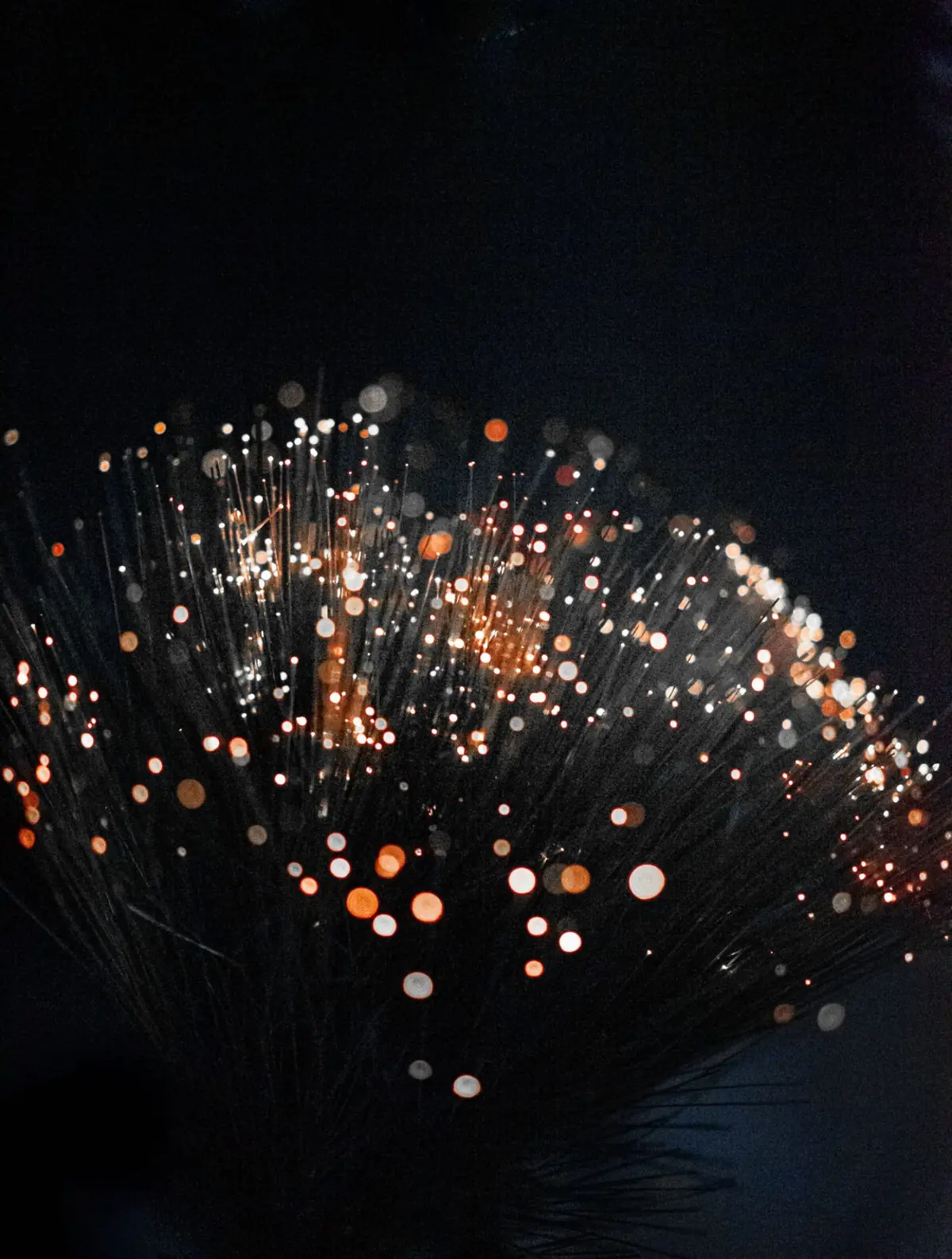 Copper-coloured light glowing at the tips of fibre optic strands